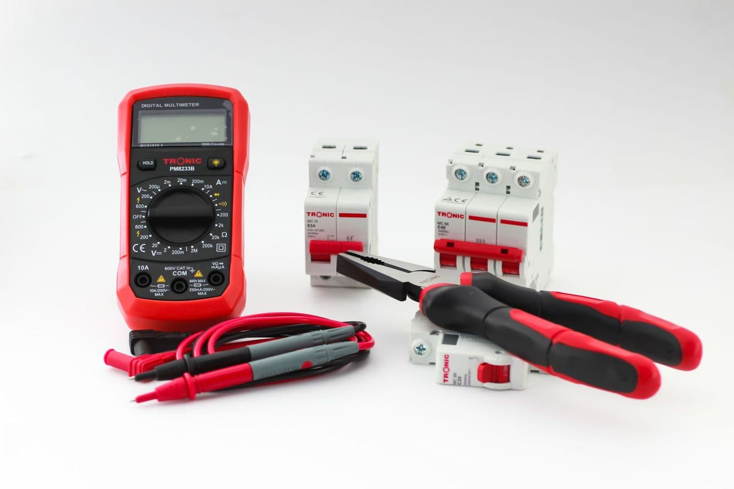 A digital multimeter, pliers and circuit breakers on a white surface